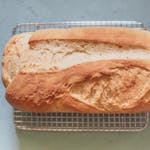 Golden brown homemade bread loaf cooling on a wire rack, ready to serve and enjoy.
