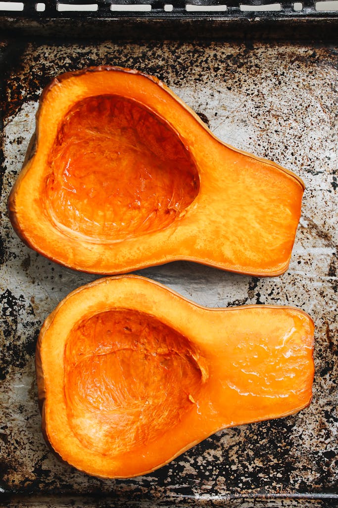 Two halves of roasted butternut squash on a rustic metal tray. Perfect for fall recipes and healthy eating.